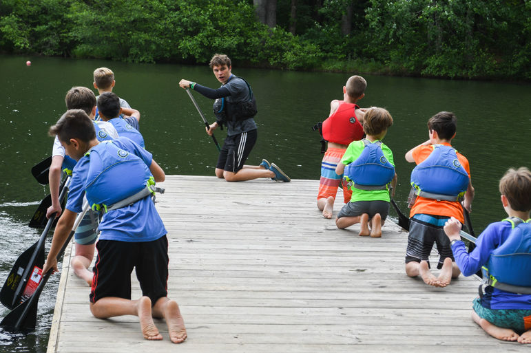 Patrick McGrady, a long-time camper and now paddling counselor, instructing a group of boys on the dock.