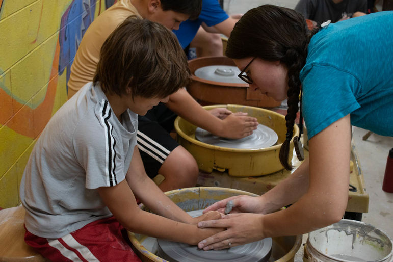 Kiera teaching boys how to throw on the wheel in pottery