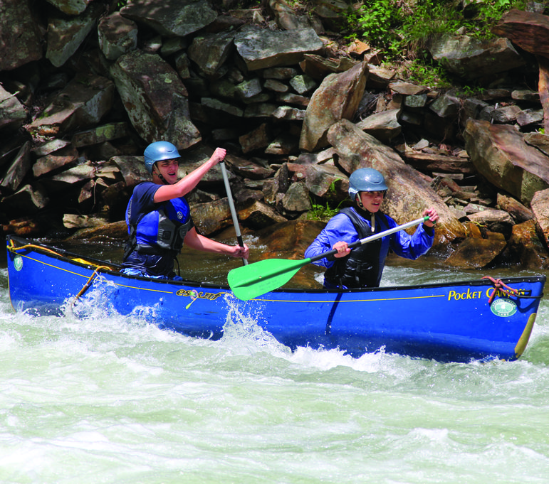 Campers in a tandem canoe on whitewater at Falling Creek Camp.