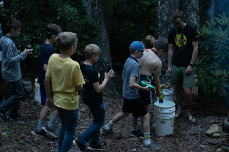 Boys contributing water to a bucket for putting out the fire